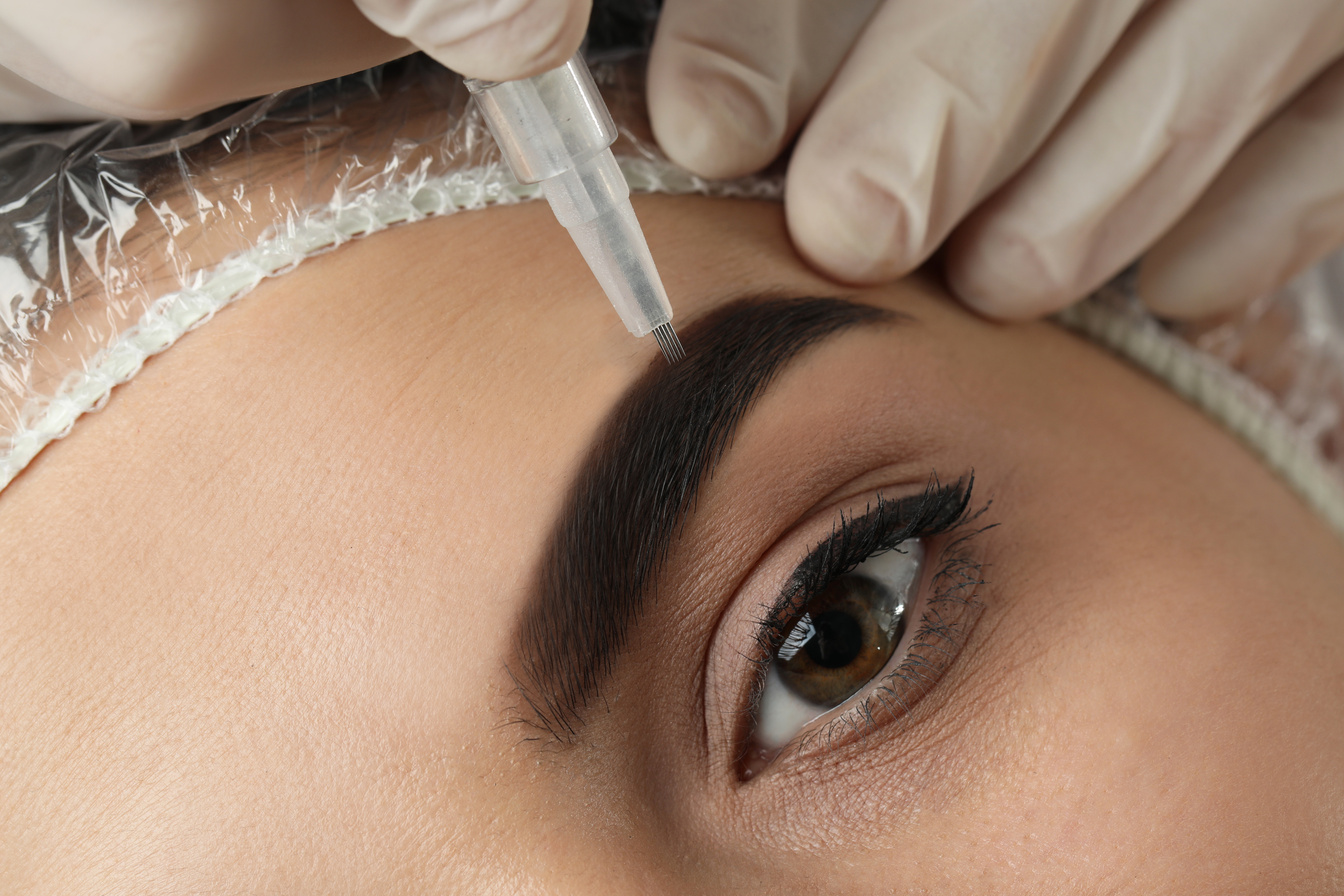 Young Woman Undergoing Procedure of Permanent Eyebrow Makeup in Salon, Closeup