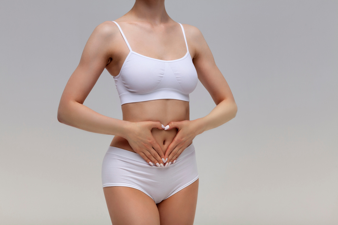Woman Holding Heart Getsure over Her Abdomen 